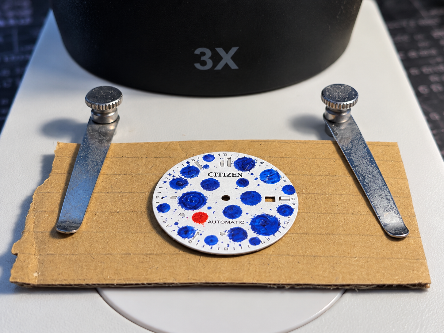 The Outlier — hand-painted dial shown in the workshop before reassembly